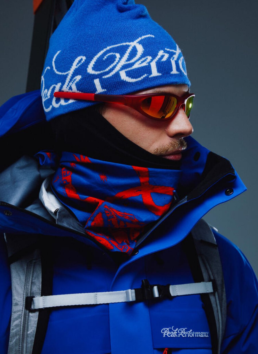 Model mit Peak Performance 40Y Mütze, Skibrille und blauer GORE-TEX Skijacke